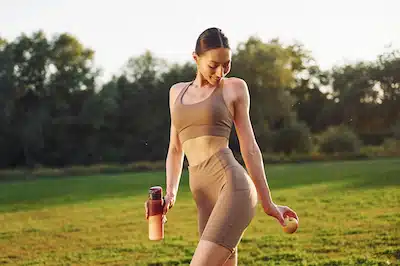 Young woman in yoga clothes is outdoors on the field