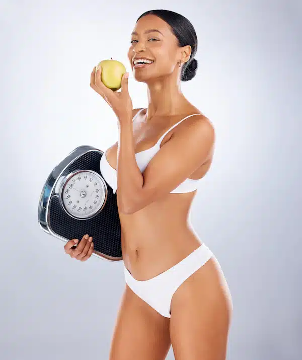 woman who successfully lost weight holding a fruit and weighing scale