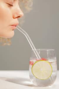 Close-up of Woman Drinking Water with Lemon through a Straw