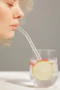 Close-up of Woman Drinking Water with Lemon through a Straw