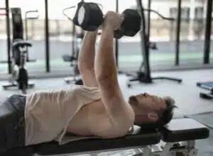 Man in White Tank Top and Grey Shorts Lifting Weights 