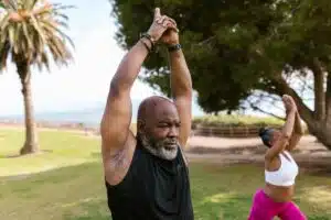 An Elderly Man in Black Tank Top Raising His Hands Together 